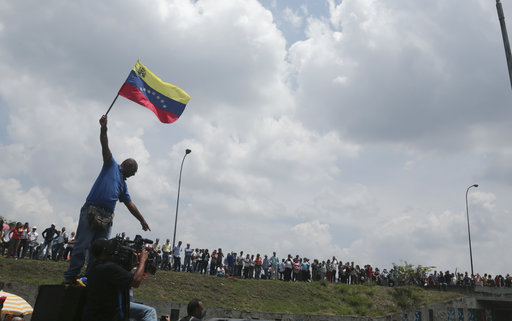 A man waves a Venezuelan national flag as anti-government protesters block a highway in Caracas
