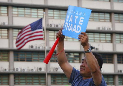 A South Korean protester holds up a card during a rally to oppose a plan to deploy the advanced U.S. missile defense system called Terminal High-Altitude Area Defense