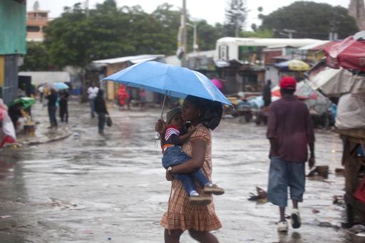 A woman carrying a child walks in the rain triggered by Hurricane Matthew in Port-au-Prince