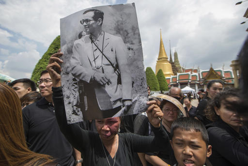 A Thai woman holds a picture of the late King Bhumibol Adulyadej as she joins other mourners to pay respect to Bhumibol at the Grand Palace in Bangkok