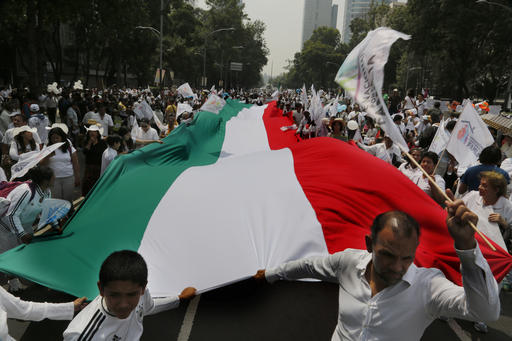 Demonstrators walk with a giant Mexican national flag during a march organized by representatives of the National Front for the Family