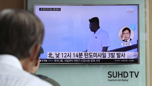 A man watches a TV news program showing a file image of North Korean leader Kim Jong Un while reporting about the North's missile launch