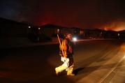 A firefighter looks for flammable items in an evacuated residential area as wildfires continue to burn Saturday