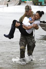 Houston Police SWAT officer Daryl Hudeck carries Catherine Pham and her 13-month-old son Aiden after rescuing them from their home surrounded by floodwaters from Tropical Storm Harvey Sunday