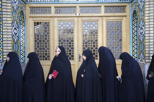 Female voters queue at a polling station for the presidential and municipal council election in the city of Qom