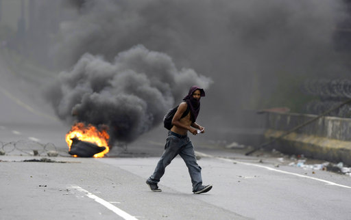 A demonstrators walks by to a burning barricaded on a highway during a national sit-in against President Nicolas Maduro