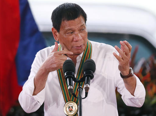 Philippine President Rodrigo Duterte gestures with a firing stance as he announces issuing side arms to army troopers during his visit to its headquarters in suburban Taguig city east of Manila