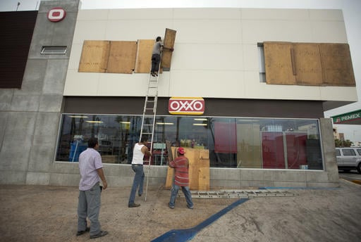 Workers board over a store front in preparation for Hurricane Newton
