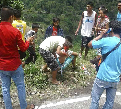 Volunteers try to rescue an injured passenger after a bus apparently lost its brakes and plunged into a deep ravine killing dozens in Carranglan township