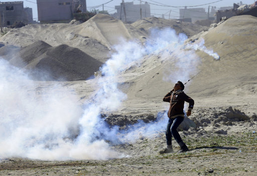 A protester uses a sling shot to throw back a tear gas canister fired by Israeli solders securing the border during clashes on the Israeli border eastern Gaza City