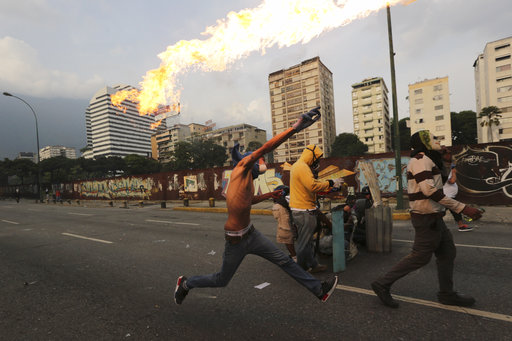An anti-government protesters throws a molotov bomb at security forces in Caracas