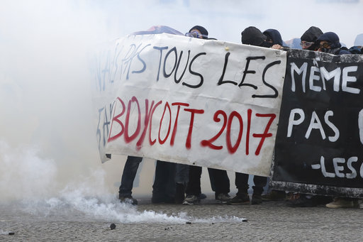 Youths shield behind a banner as Paris police are firing tear gas