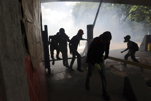 Students run from tear gas fired by National Police outside the Central University of Venezuela in Caracas