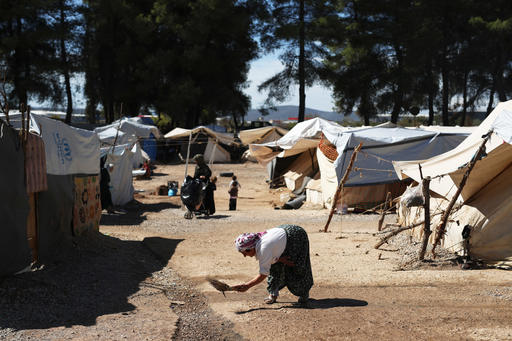 A woman sweeps a path among the tents at the Ritsona refugee camp north of Athens