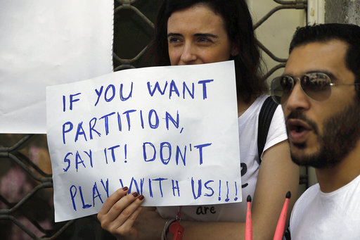 A woman holds banner as people gather across the Ledras main crossing point inside the U.N buffer zone