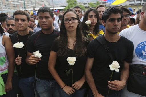 Protesters in black carry white flowers during a silent protest in homage to the at least 20 people killed in unrest generated after the nation's Supreme Court stripped congress of its last powers
