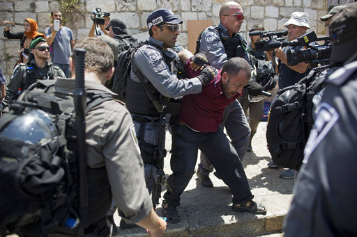 Israeli police officers detain a Palestinian man outside the Lion's Gate