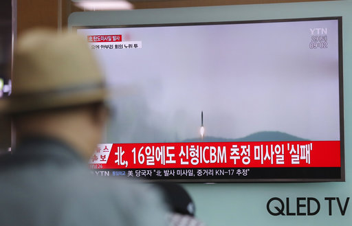 A man watches a TV news program reporting about North Korea's missile firing with a file footage