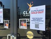 An eclipse glasses sold out sign is posted outside the Clark Planetarium main doors advising people to safely view the eclipse with a pinhole projector after the planetarium ran out of glasses Thursday