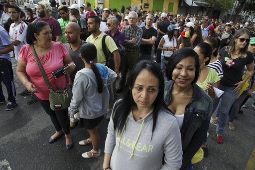 People line up to cast their ballots at a poll station during a symbolic referendum in Caracas