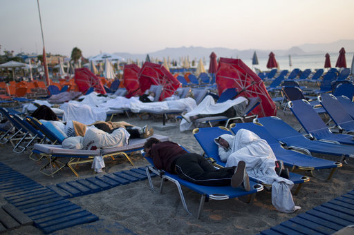 Tourist sleep on sun beds at a beach of the Greek island of Kos
