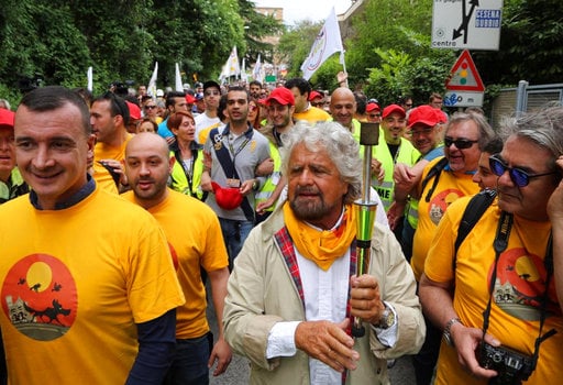 Italian Five Stars Movement's leader Beppe Grillo holds a torch as he takes part to a march from Perugia to Assisi