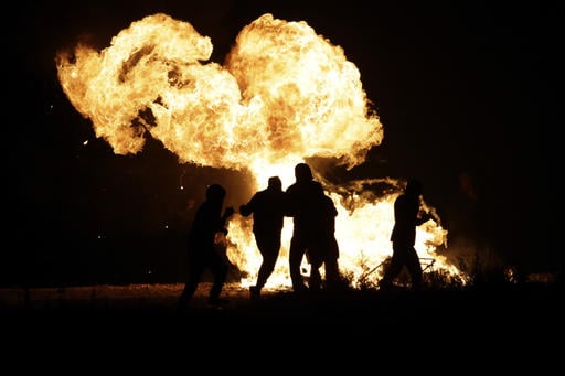 Migrants run past a fire near a makeshift migrant camp known as "the jungle" near Calais