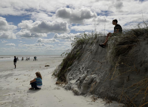 A boy sits on a cliff formed by erosion from Hurricane Matthew on the beach at Jacksonville Beach