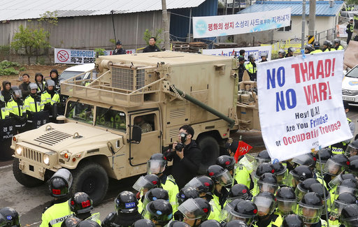 U.S. military vehicle moves past banners opposing a plan to deploy an advanced U.S. missile defense system called Terminal High-Altitude Area Defense