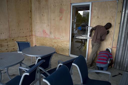 Workers  set up a board  as protection against hurricane Matthew in an hotel in Kingston