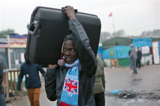 An unidentified migrant carrying his luggage leaves a makeshift camp known as "the jungle" near Calais