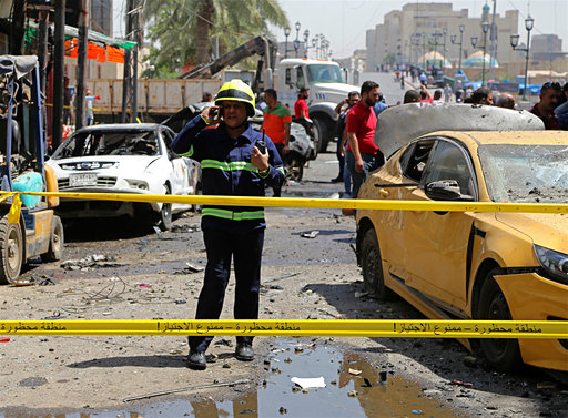 Iraqi security forces and civilians inspect the site of a deadly bomb attack