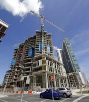 A high-rise building under construction is shown next to a high-rise condominium building