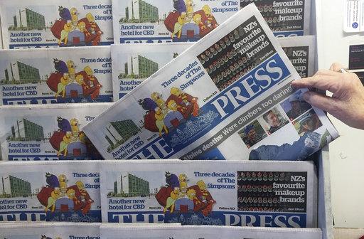 A shop owner stacks editions of the "The Press" newspaper