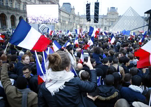 People wave French flags at the Louvre museum where Emmanuel Macron is planning to celebrate