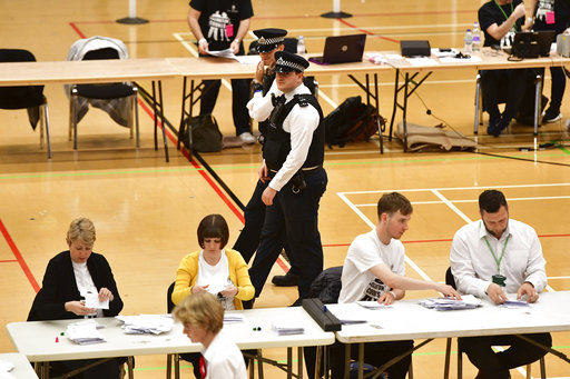Police officers walk past as votes cast in the general election are counted in Islington in London