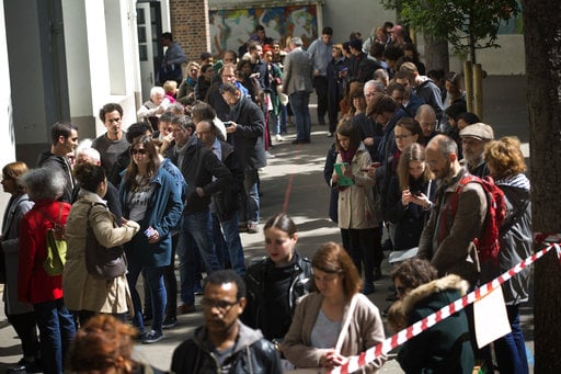 People line up before casting their vote for the first-round presidential election at a polling station in Paris