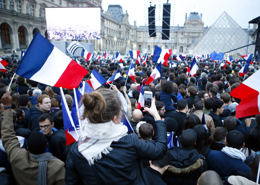 People wave French flags at the Louvre museum where Emmanuel Macron is planning to celebrate