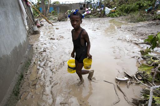 A girl lugs buckets of drinking water after the passing of Hurricane Matthew in Les Cayes