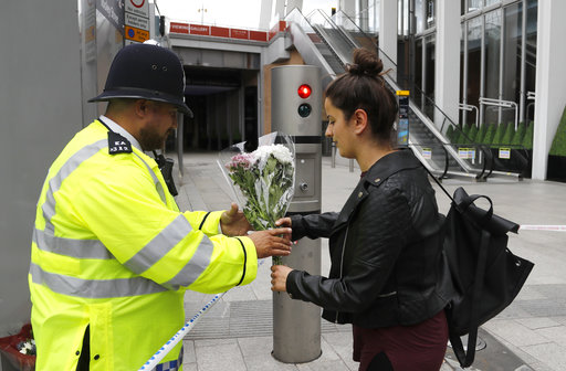 A woman hands a bouquet of flowers to be left in the London Bridge area of London