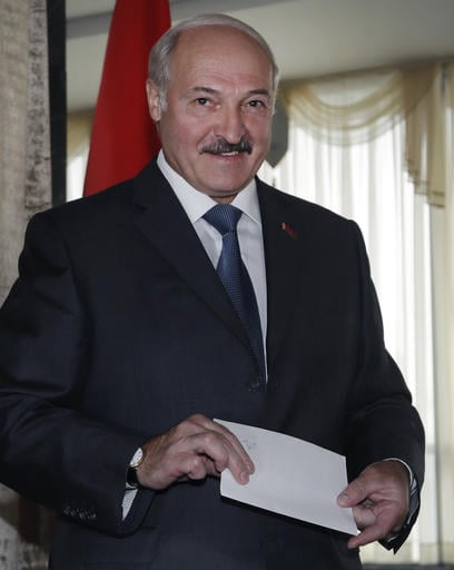 Belarusian President Alexander Lukashenko smiles at photographers as he prepares to cast his ballot during parliamentary elections in Minsk