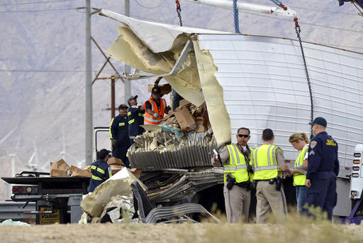 Workers remove debris from a semi-truck that crashed with a tour bus on Interstate 10
