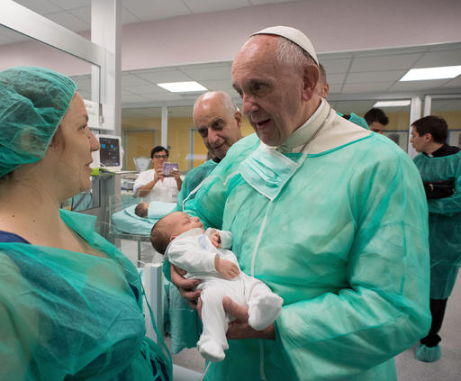Pope Francis holds a baby during a visit to the neonatology division of the San Giovanni hospital in Rome