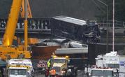 A damaged Amtrak train car is lowered from an overpass at the scene of Monday's deadly train crash onto Interstate 5 Tuesday