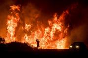 FILE - A motorist on Highway 101 watches flames from the Thomas fire leap above the roadway north of Ventura
