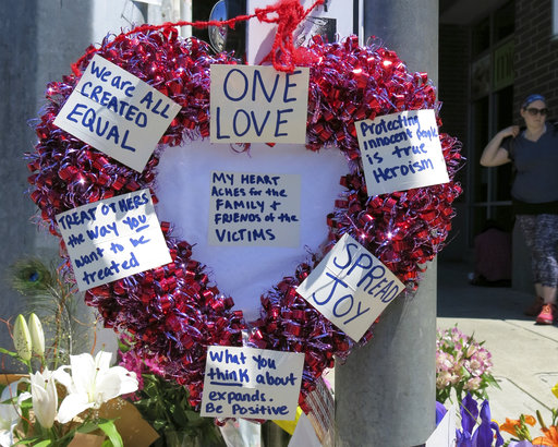 A heart-shaped wreath covered with positive messages hangs on a traffic light pole at a memorial for two bystanders who were stabbed to death Friday