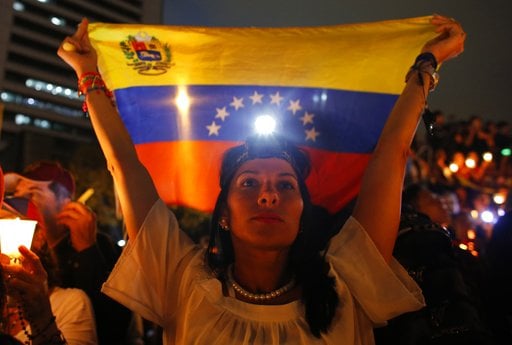 A demonstrator holds a Venezuelan flag during a vigil for the victims of the clashes with the government's security forces