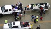 Evacuees are helped as floodwaters from Tropical Storm Harvey rise Tuesday