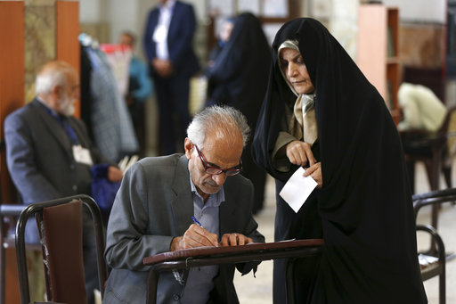 A man fills out his ballots to vote in the presidential and municipal council election in Tehran