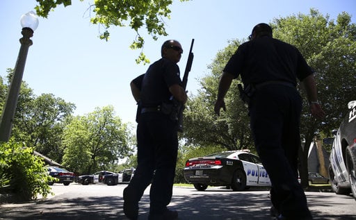 Dallas Police walk a neighborhood a block away from a shooting in Dallas